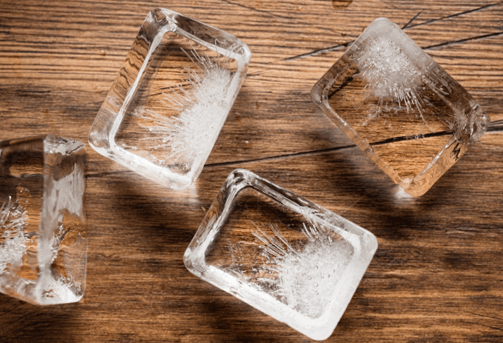 Cubetti di ghiaccio che si sciolgono su superficie di legno